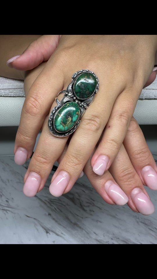 Clean nude gel nails paired with a green stone ring